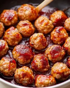 Tangy cranberry turkey meatballs served on a plate with sauce and herbs.